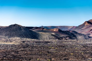 Yanan volkanik kraterlerin, volkanik küllerin ve lav nehirlerinin eşsiz dramatik panoramik görüntüsü. Timanfaya Ulusal Parkı Mars manzarası, Lanzarote, Kanarya Adaları, İspanya.