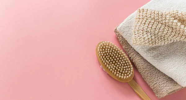 Body brush for anti-cellulite massage and skin treatment with soft towels on pink background. Lay out design with copy space. Cactus long handle exfoliating brush for body care