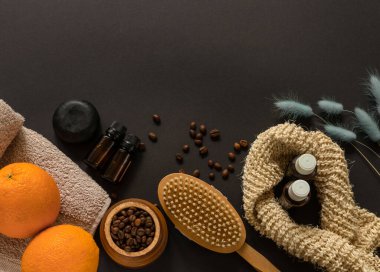 Ev spa konsepti. Vücut fırçası, sabun, havlu, portakal, kahve çekirdeği ve anti-selülit masajı için gerekli yağ ve cilt bakımı siyah arka plan. Düz dizayn. Ev soyma