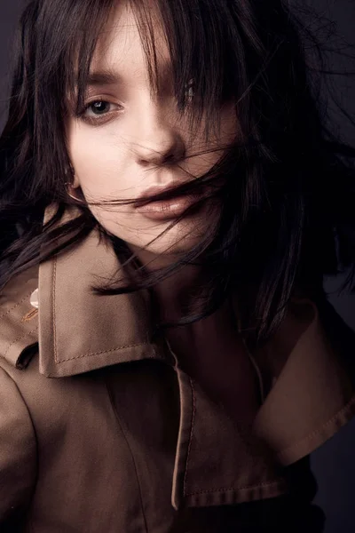 ベージュのトレンチ コートを着て裸化粧 黒い髪と美しい官能的な女性の肖像画間近で暗い スタジオ撮影 — ストック写真