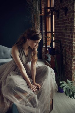 Büyülü genç kadın ile masaya oturan kafasına kuş tüyü taç uzun hafif zeytin tül elbise 