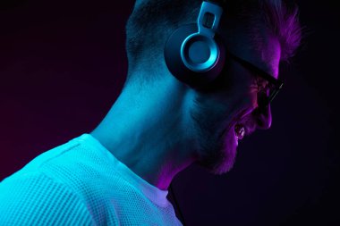 Neon kulaklıklar, güneş gözlüğü, beyaz t-shirt sakallı gülümseyen adam portresi. Müzik 