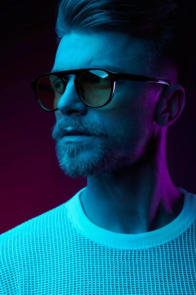 stock image Neon light studio portrait of serious man model with mustaches and beard in sunglasses and white t-shirt 