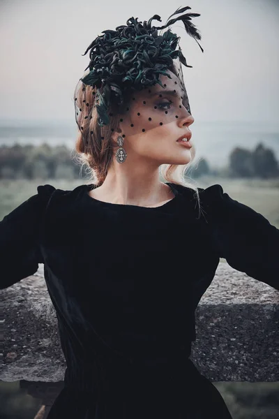 Siyah elbise ve örtü ile koyu yeşil fascinator güzel kadın inanılmaz açık portresi. Victoria bakmak.