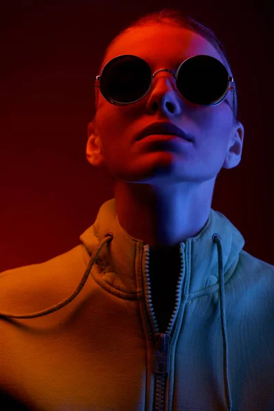 Neon portrait of young woman in round sunglasses. Studio shot