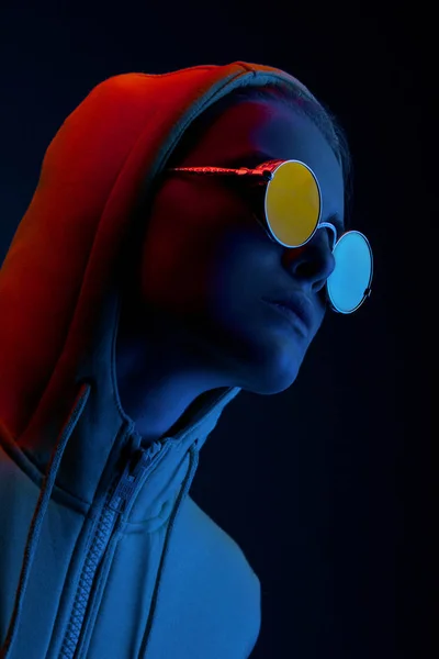 Neon portrait of young woman in round sunglasses. Studio shot