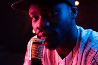 Genç erkek soul şarkıcısı mikrofon ile yakın çekim portre. Pembe neon ışık