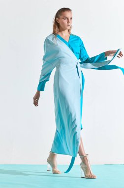 Tam uzunlukta moda turkuaz ve mavi elbiseli Genç kadın portresi. Stüdyo, beyaz arka plan 