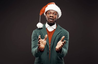 Modern Noel Baba. Yeşil ceket ve santa çantası ile kırmızı kazaklı adam elinde gülümseyerek. Atış, arka plan siyah stüdyo