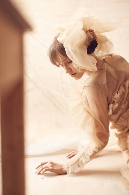 Yumuşak Güzellik Portresi olan mavi gözleri ve bang, suni tül saç aksesuarı ile çıplak tül elbise rüya gibi kadın. Kızı yerde yatıyor. Stüdyo vurdu