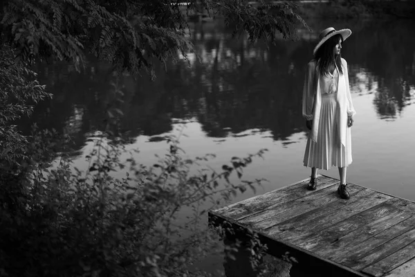 黑白梦幻肖像的女人在复古的衣服和草帽 走在池塘附近的码头 — 图库照片