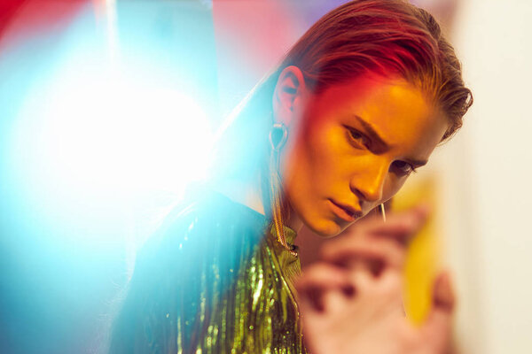 Fashion portrait of young sexy woman with wet hair, in golden dress. Glare in frame, red background