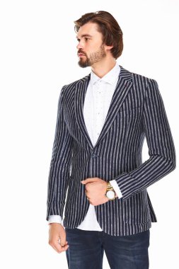 sakallı ve koyu saçlı bir adam beyaz bir arka plan üzerinde bir nokta ve çizgili ceket beyaz bir arka plan üzerinde duruyor o kolunda altın bir saat var ve lef bakar