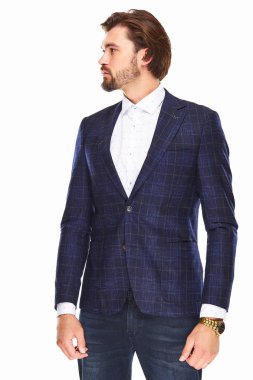 sakallı ve koyu saçlı bir adam beyaz bir arka plan üzerinde bir nokta ve damalı ceket beyaz bir arka plan üzerinde duruyor o kolunda altın bir saat var ve lef bakar