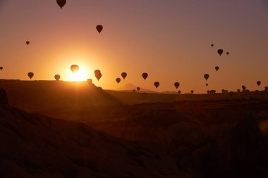 Kapadokya 'da gündoğumu fotoğrafı gökyüzünde balonlarla kumlu tepeler üzerinde