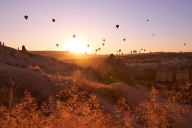 Kapadokya 'da gündoğumu fotoğrafı gökyüzünde balonlarla kumlu tepeler üzerinde