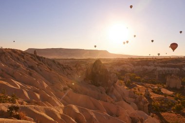 Kapadokya 'da sabah fotoğrafı. Mavi gökyüzünde balonlarla kumlu tepeler üzerinde.