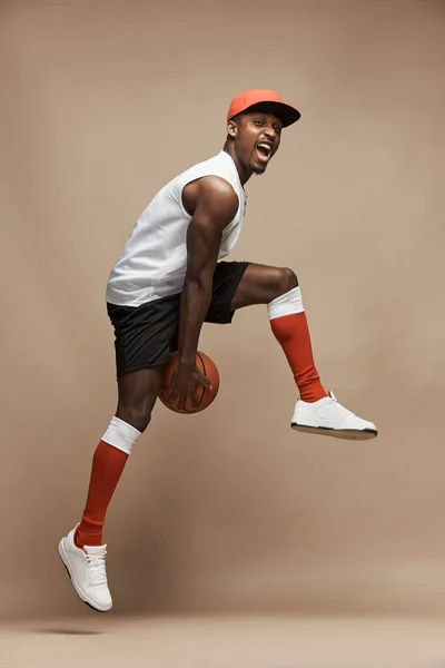 Pełnowymiarowe Zdjęcie Czarnego Koszykarza Sportowego Studio Beżowym Tle Skaczącego Wysoko — Zdjęcie stockowe