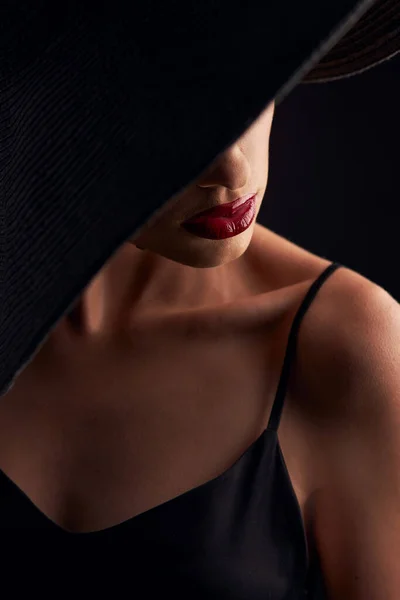 プロの化粧をした美しい日焼けした女の子の肖像画 赤い唇 ストラップと黒の帽子と黒のドレスで彼女の目をカバー — ストック写真