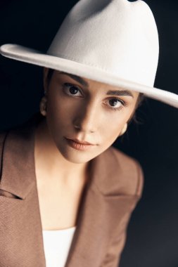 portrait photo of a beautiful stylish girl in a brown suit, white top and white hat, she mysteriously looks into the camera with her brown eyes clipart
