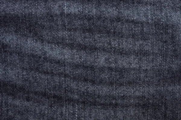 Crumpled black oe dark gray jeans texture as background. Top view