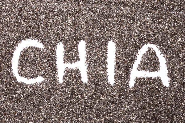 Word CHIA made of chia seeds on white background, healthy superfood. Top view