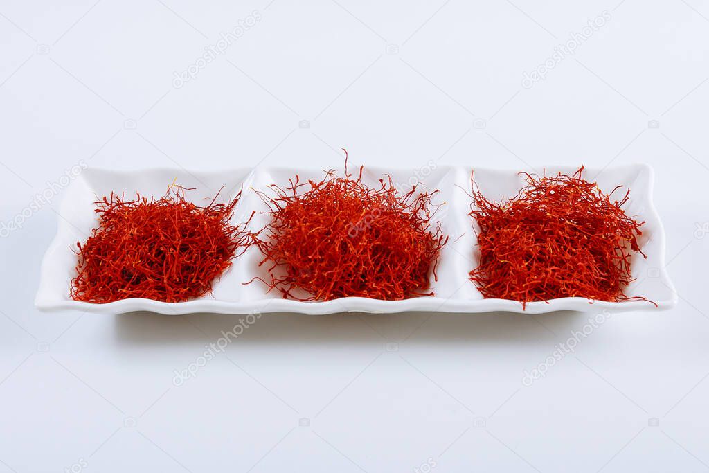 Dry Saffron Spice on a Plate on white Background. The use of saffron in cooking, medicine, cosmetology.