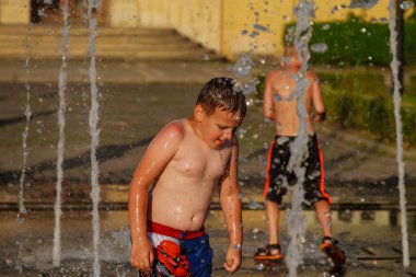 Uzhhorod, Ukrayna, 30 Haziran 2019: Çocuklar sıcak bir yaz günü çeşmede yıkanırlar.