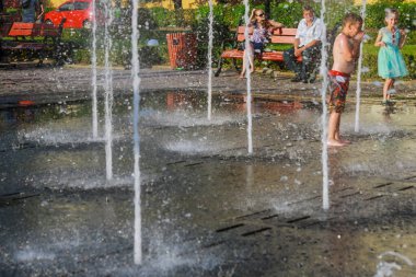 Uzhhorod, Ukrayna, 30 Haziran 2019: Çocuklar sıcak bir yaz günü çeşmede yıkanırlar. Yumuşak odaklı insanlar.