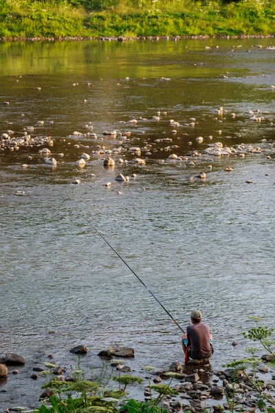 Рыбак рыбачит на удочке в реке — стоковое фото