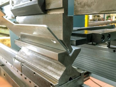 Bending sheet metal with a hydraulic bending machine at the factory. clipart