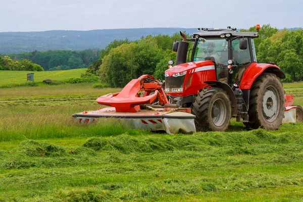 Grote rode trekker met twee maaiers maait het gras voor kuilgras — Stockfoto