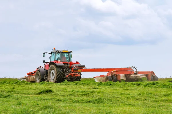 Großer roter Traktor mit zwei Mäher mäht das Gras für Silage — Stockfoto