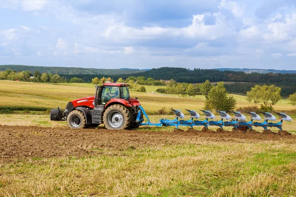 Ein Traktor mit einem großen Pflug pflügt ein Feld um. Traktor mit landwirtschaftlichem Anbaugerät. — Stockfoto