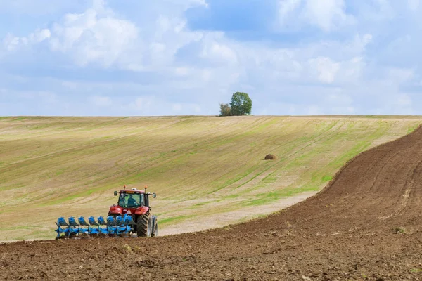 Трактор с большим плугом вспахивает поле. Трактор с аграрным креплением . — стоковое фото