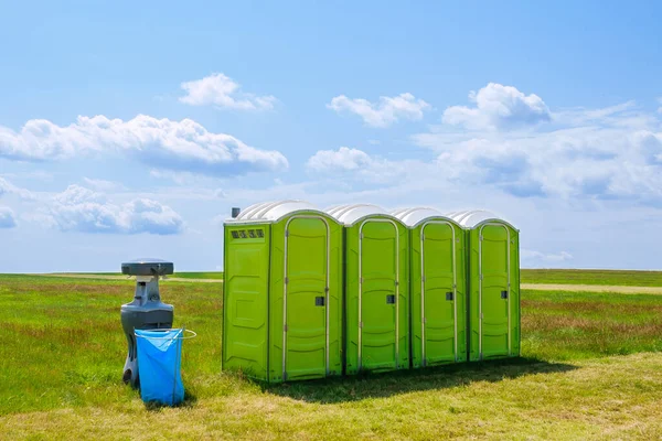 Toilet portabel di rumput di latar belakang awan. — Stok Foto