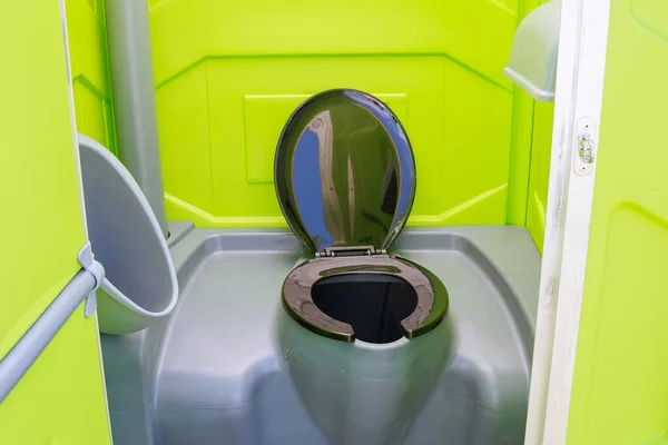 Çimlerin üzerinde portatif tuvalet açık kapılı bulutların arka planında. Mobil tuvalet.