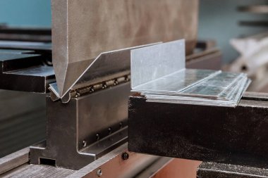 Fabrikadaki hidrolik bir makinede metal bükme levhası. Yakın plan..