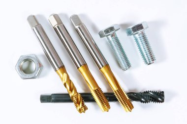 Metal iplik seti. Beyaz arka planda cıvatalar ve fındıklar var. Metal işleme aracı.