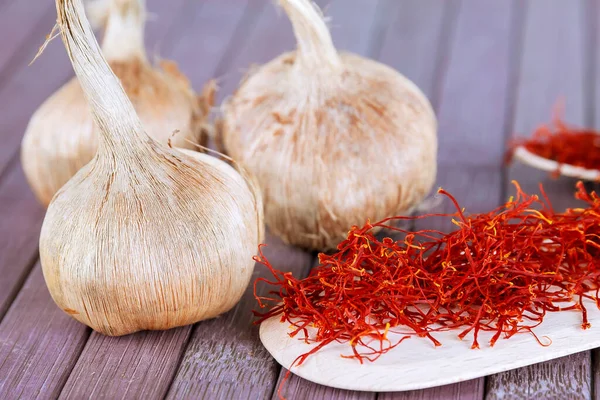 Bulbs of crocus sativus, dry spice saffron in wooden spoon on a wooden background. — Stock Image Bulbs of crocus sativus, dry spice saffron in wooden spoon on a wooden background. Stock Image
