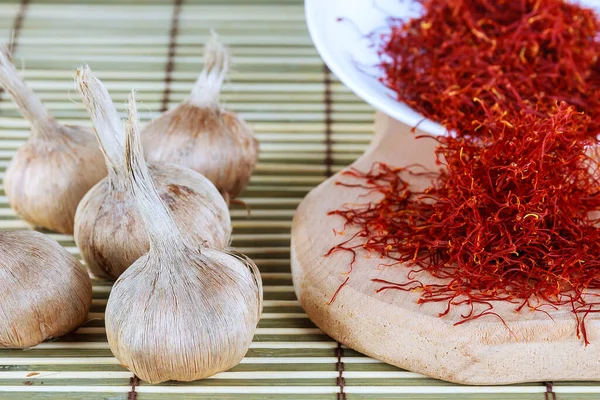 Bulbs of crocus sativus, dry spice saffron in wooden board on a wooden background. — Stock Image Bulbs of crocus sativus, dry spice saffron in wooden board on a wooden background. Stock Picture