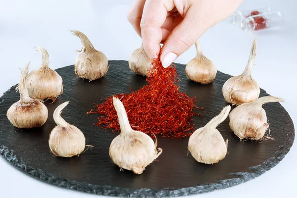 Saffron sativus bulb and dry spice of saffron on a black board on white background. Pile red stamen of saffron. — Stock Image Saffron Sativus Bulb Dry Spice Saffron Black Board White Background Stock Picture