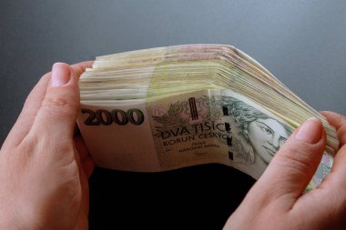 Siyah arka plandaki bir kadının elinde bir deste Çek parası. 2000 'in banknotları.
