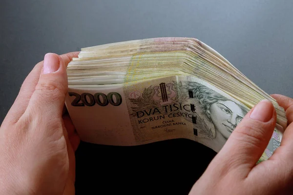 Siyah arka plandaki bir kadının elinde bir deste Çek parası. 2000 'in banknotları.