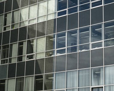 Gri ve mavi tonlu bir ofis binasının pencereleri