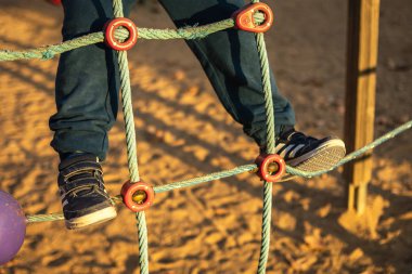 Parkta oynayan bir çocuk ağa tırmanıyor.
