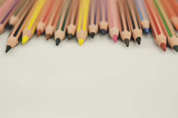 Beyaz arkaplandaki renkli kalemler izleyiciyi işaret ediyor