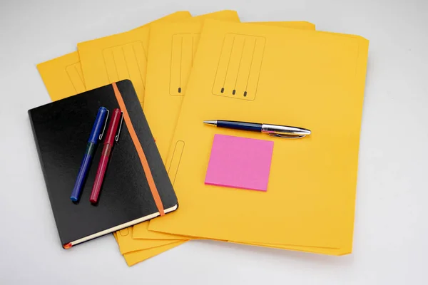 Sarı alt klasörler üzerinde fuşya not defteri olan modern tükenmez kalem. — Stok fotoğraf