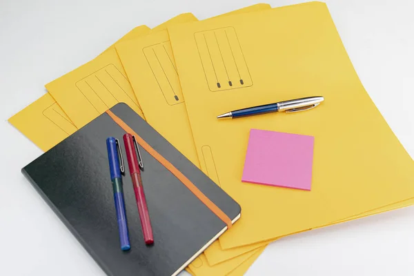 Kırmızı ve mavi kalemler, kalem, yapışkan notlar ve sarı su üzerindeki not defteri. — Stok fotoğraf