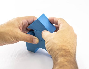 Bir adamın elleri, bir çocuk oyuncağının yapıcı unsurlarıyla bir yapı gerçekleştirir.